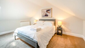 Une chambre à coucher avec un lit, des lampes de chevet, un radiateur et un tableau au mur.