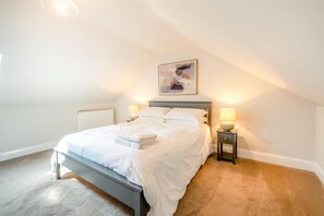 Ein Schlafzimmer mit einem Bett, Nachttischlampen, einem Heizkörper und einem Bild an der Wand.