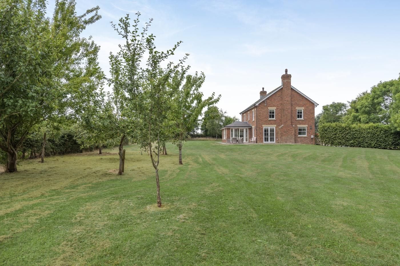 A brick house with a lawn and trees.