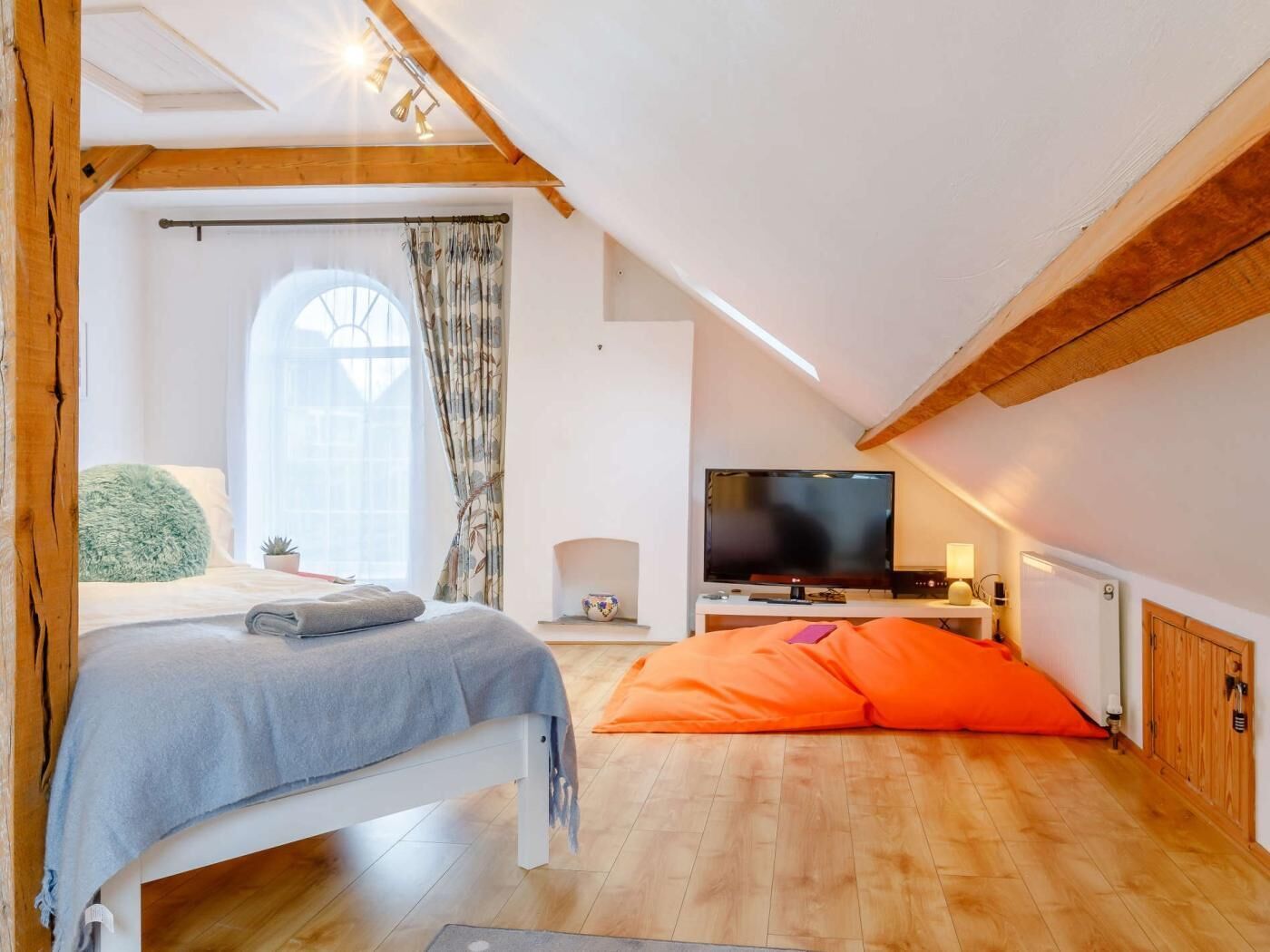 Une chambre à coucher avec un lit, une télévision, une fenêtre avec des rideaux et un plafond en bois.