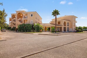 A multi-story hotel with balconies, a central courtyard, and a palm tree. - Apartment 'Virpi's Place Vilamoura' with Private Pool, Wi-Fi and Air Conditioning (Quarteira)