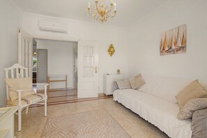 A white room with a bed, a chair, a table, and a painting on the wall. - Apartment 'Virpi's Place Vilamoura' with Private Pool, Wi-Fi and Air Conditioning (Quarteira)