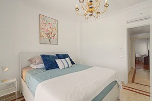 Une chambre à coucher avec un lit, une table de chevet, une lampe et un lustre.