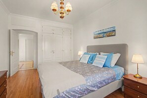 Ein Schlafzimmer mit Bett, Nachttisch, Kommode, Kleiderschrank und einer Chandelier.