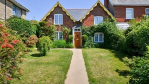 A two-story brick house with a central entrance, a garden with a pathway, and a neighboring building. - 3 Bed in Sandown (oc-85985) (Sandown)