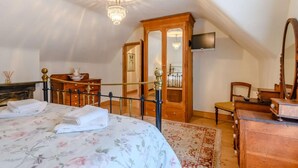 A bedroom with a bed, a wooden dresser, a mirror, a chandelier, and a television. - 3 Bed in Sandown (oc-85985) (Sandown)