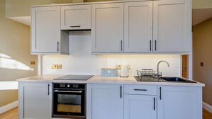 A modern kitchen with light grey cabinets, a built-in oven, a sink, and a countertop with a kettle and a dish rack. - 2 Bed in Hawick (oc-86021) (Hawick)