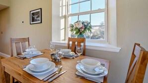 A dining table set with plates, bowls, glasses, and cutlery, positioned near a window with a view of trees. - 2 Bed in Hawick (oc-86021) (Hawick)