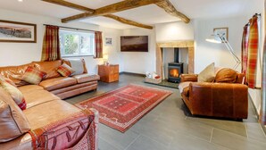 Ein gemütliches Wohnzimmer mit Kamin, Ledersofas und einem roten Teppich.