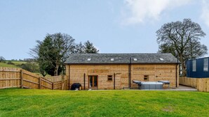 A wooden building with a fenced yard, a hot tub, and a covered outdoor seating area. - 4 Bed in Llandrindod Wells (oc-86118) (Llaithddu)