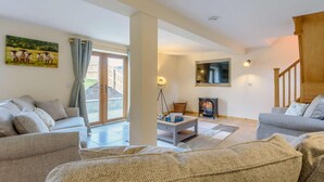A living room with a sofa, a coffee table, a TV, and a fireplace. - 4 Bed in Llandrindod Wells (oc-86118) (Llaithddu)