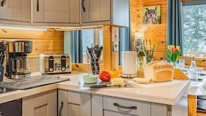A modern kitchen with wooden cabinets, a coffee maker, a toaster, and a bread loaf on the counter.