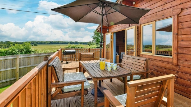 A wooden deck with a table, chairs, and a barbecue grill.