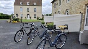 Un estacionamiento con bicicletas, un edificio de fachada de piedra y una pequeña zona de estar al aire libre.