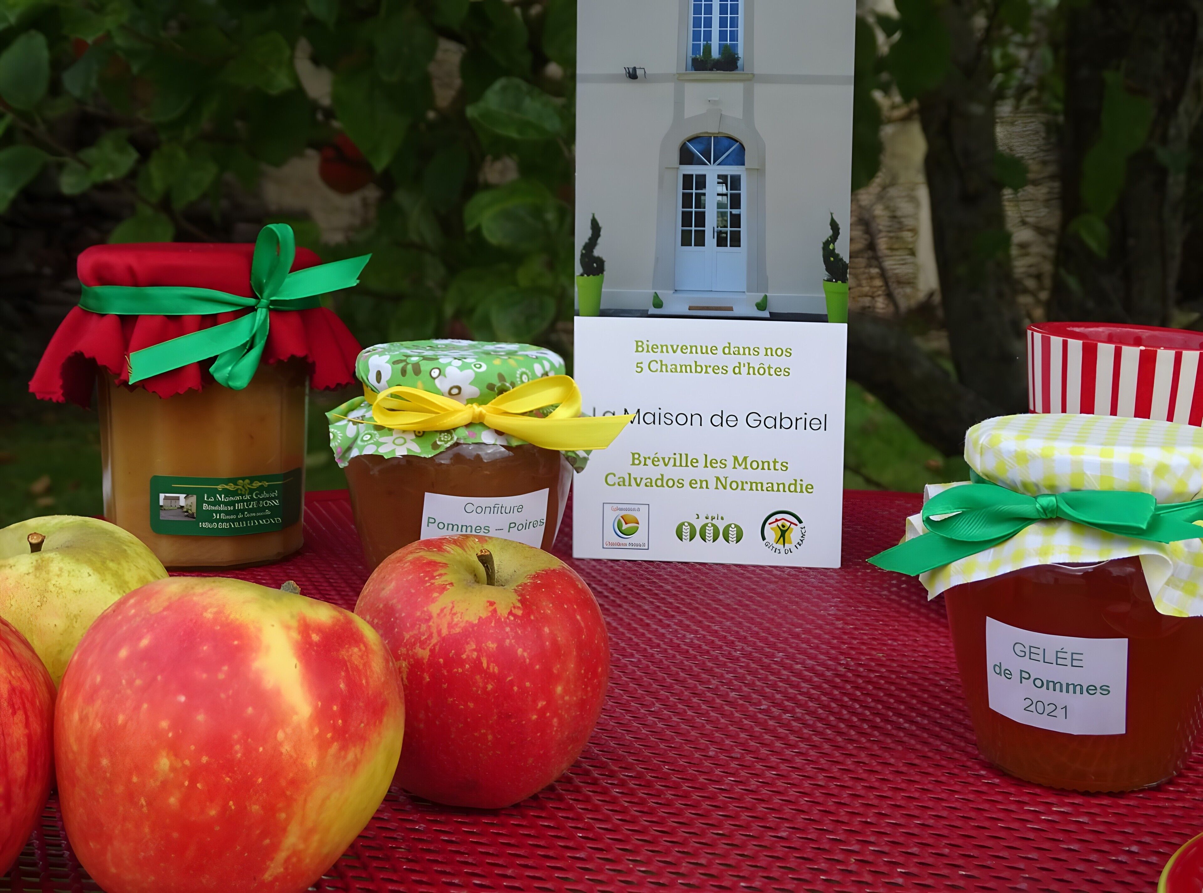 A table with jars of apple jam, apples, and a sign with a house illustration.