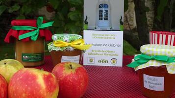 A table with jars of apple jam, apples, and a sign with a house illustration.