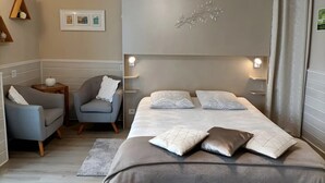 Un dormitorio con cama, dos mesitas de noche, una silla, un estante pequeño e iluminación en la pared.