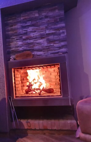 A fireplace with a stone facade and a lit fire. - Charming villa, not overlooked (Hammamet)