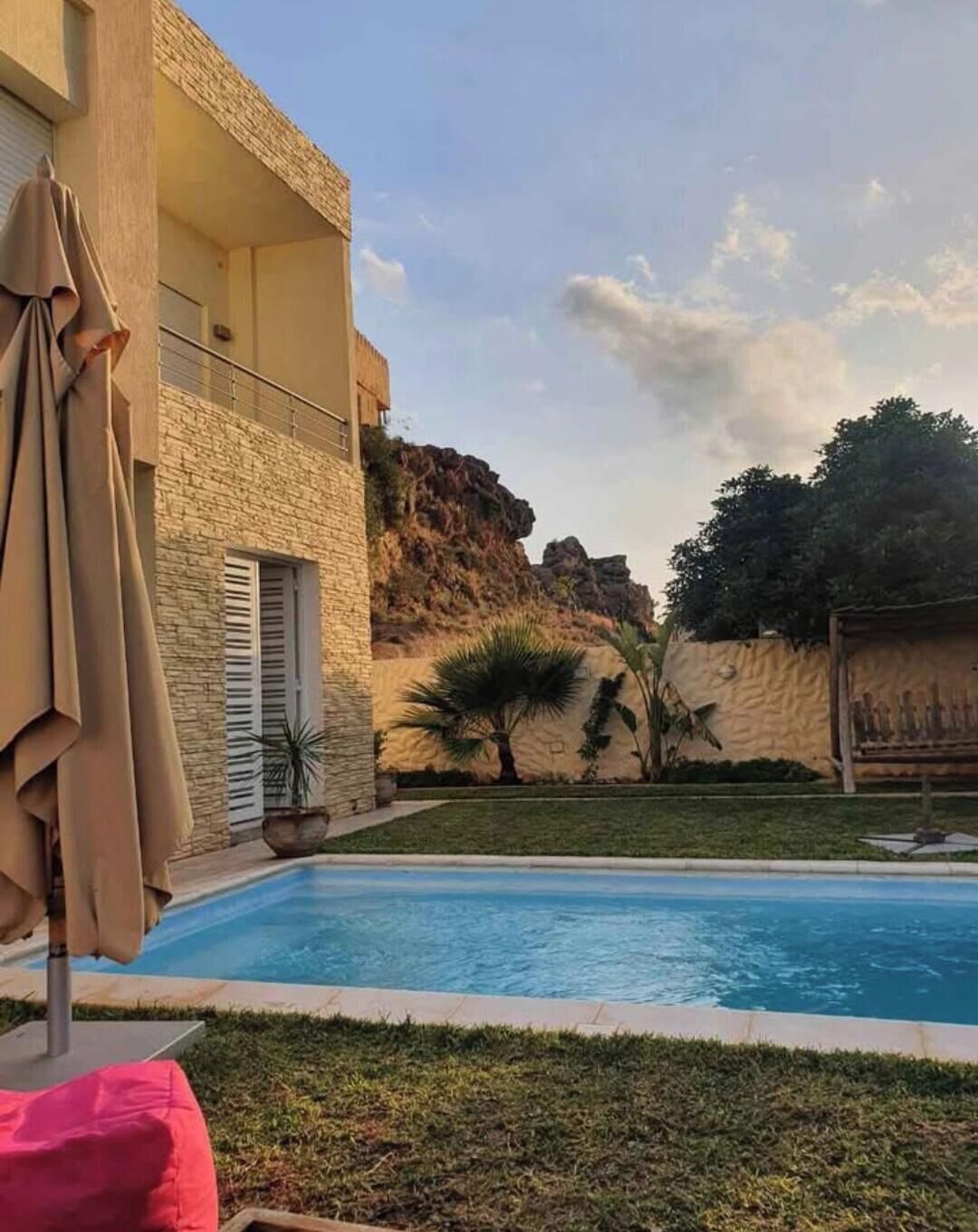 Une piscine avec un bâtiment en pierre et une chaîne de montagnes en arrière-plan.
