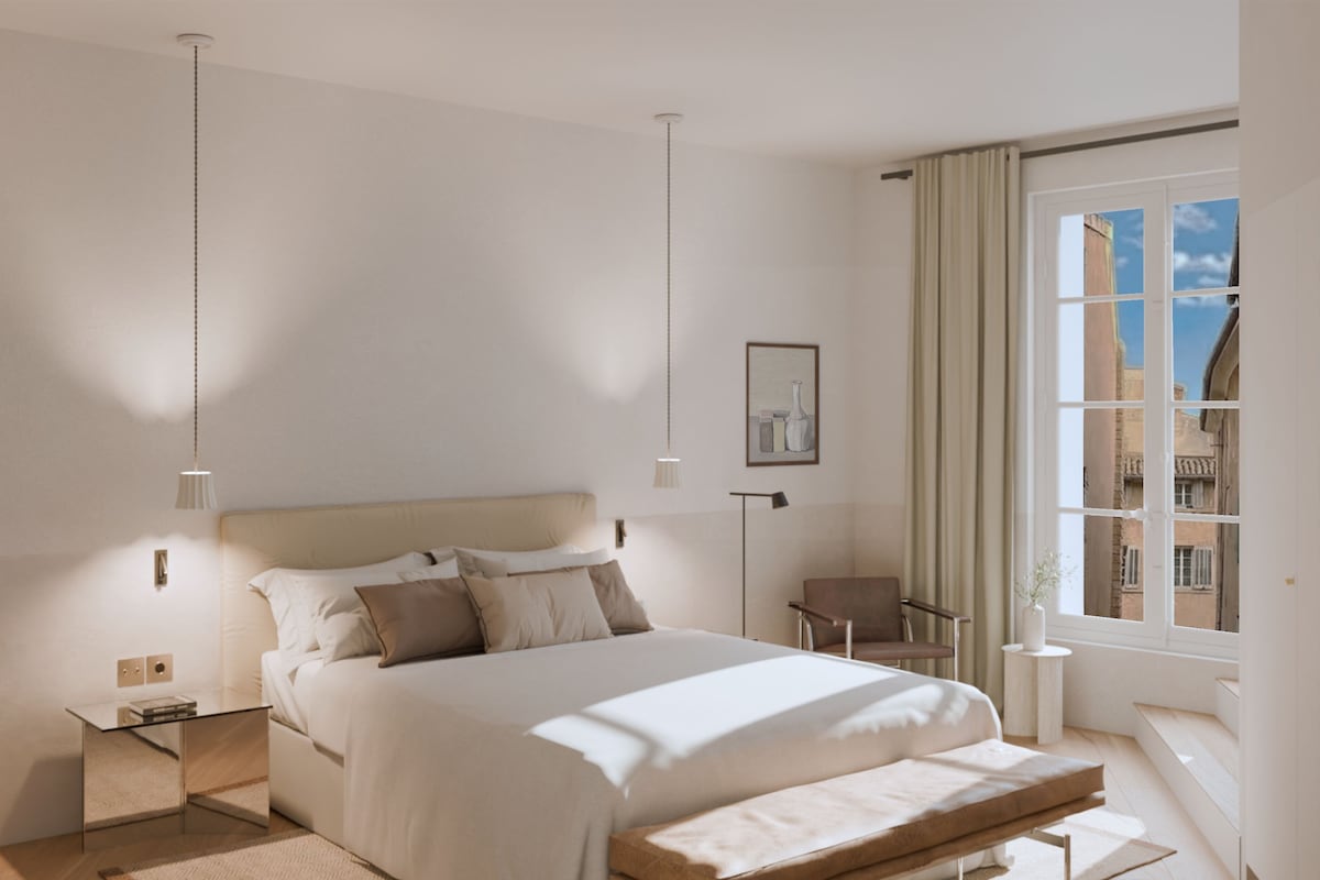 Un dormitorio moderno con una cama grande, mesitas de noche, una silla y un ventanal con vistas.