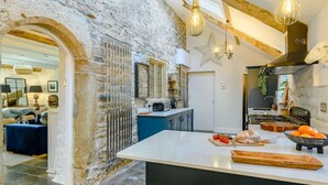 A rustic kitchen with exposed beams, a central island, and a stone wall. - 8 Bed in Bridgend (oc-86493) (Southerndown)