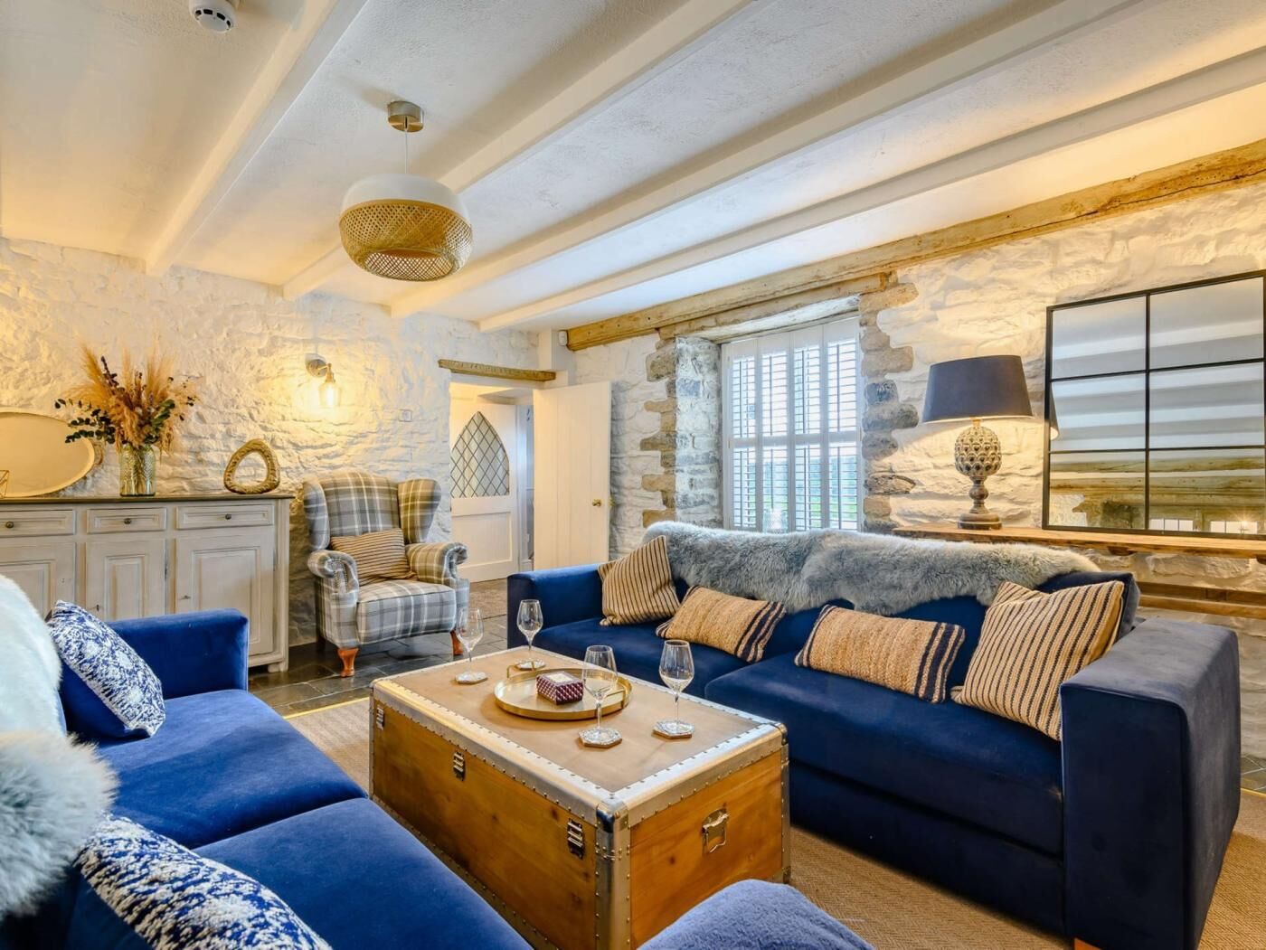 A cozy living room with a blue sofa, a wooden coffee table, and a stone wall.