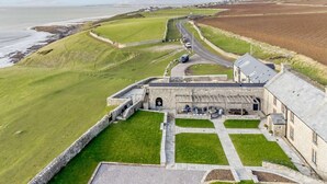 A coastal fort with a paved courtyard, stone walls, and a view of the sea. - 8 Bed in Bridgend (oc-86493) (Southerndown)