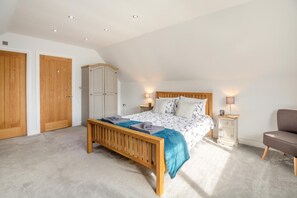A bedroom with a wooden bed, a wardrobe, a chair, and a nightstand with a lamp. - 4 Bed in Caernarfon (oc-86423) (Penygroes)