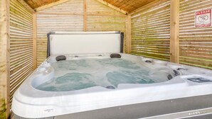 Ein Whirlpool mit Holzdach und -wänden, ein Schild mit der Bitte um Ruhe sowie das Logo von Aspen Spas.