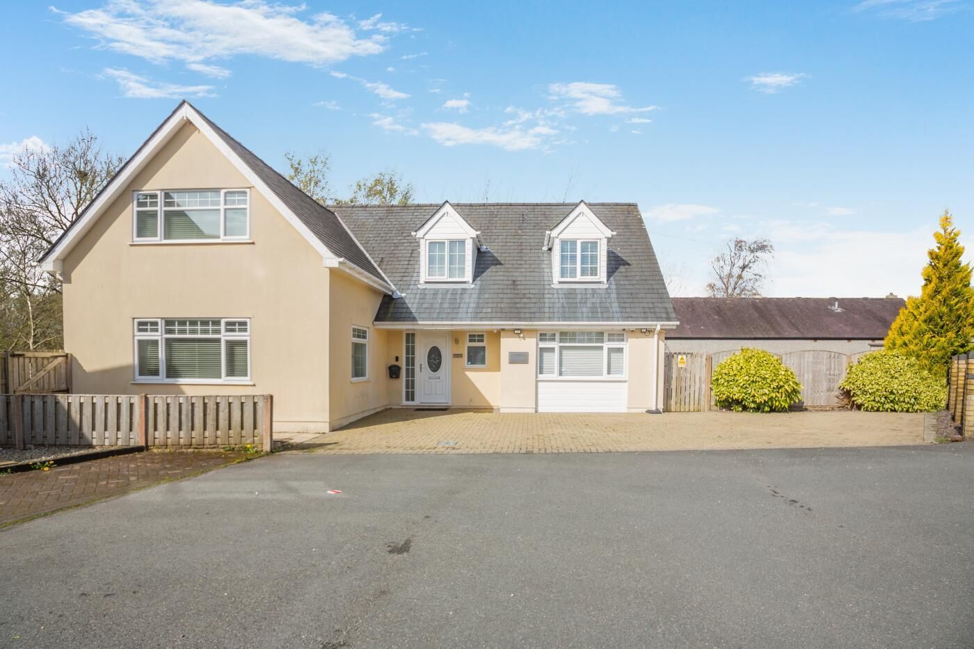 Ein zweistöckiges Haus mit Garage, Auffahrt und umzäunter Garten.