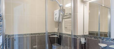 A modern bathroom with a glass shower enclosure, a toilet, and a sink with a mirror.