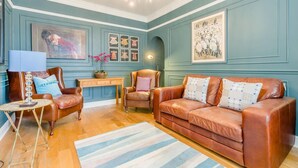 Ein Wohnzimmer mit braunem Ledersofa, einem Holztisch und einem blau-weiß gestreiften Teppich.