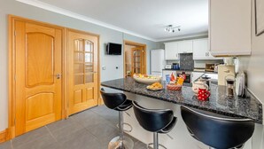 Eine Küche mit einer Granitabdeckung, Holzschränken, einem Fernseher und einer Kaffeemaschine.