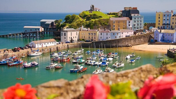 A coastal town with a historic building, a pier, and a variety of boats docked at the harbor. - 3 Bed in Tenby (oc-86625) (Tenby)