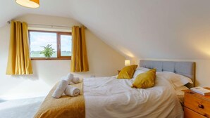 A bedroom with a bed, two pillows, a bedside table, a lamp, a window with curtains, and a view of the outdoors. - 2 Bed in Lampeter (oc-86507) (Cellan)