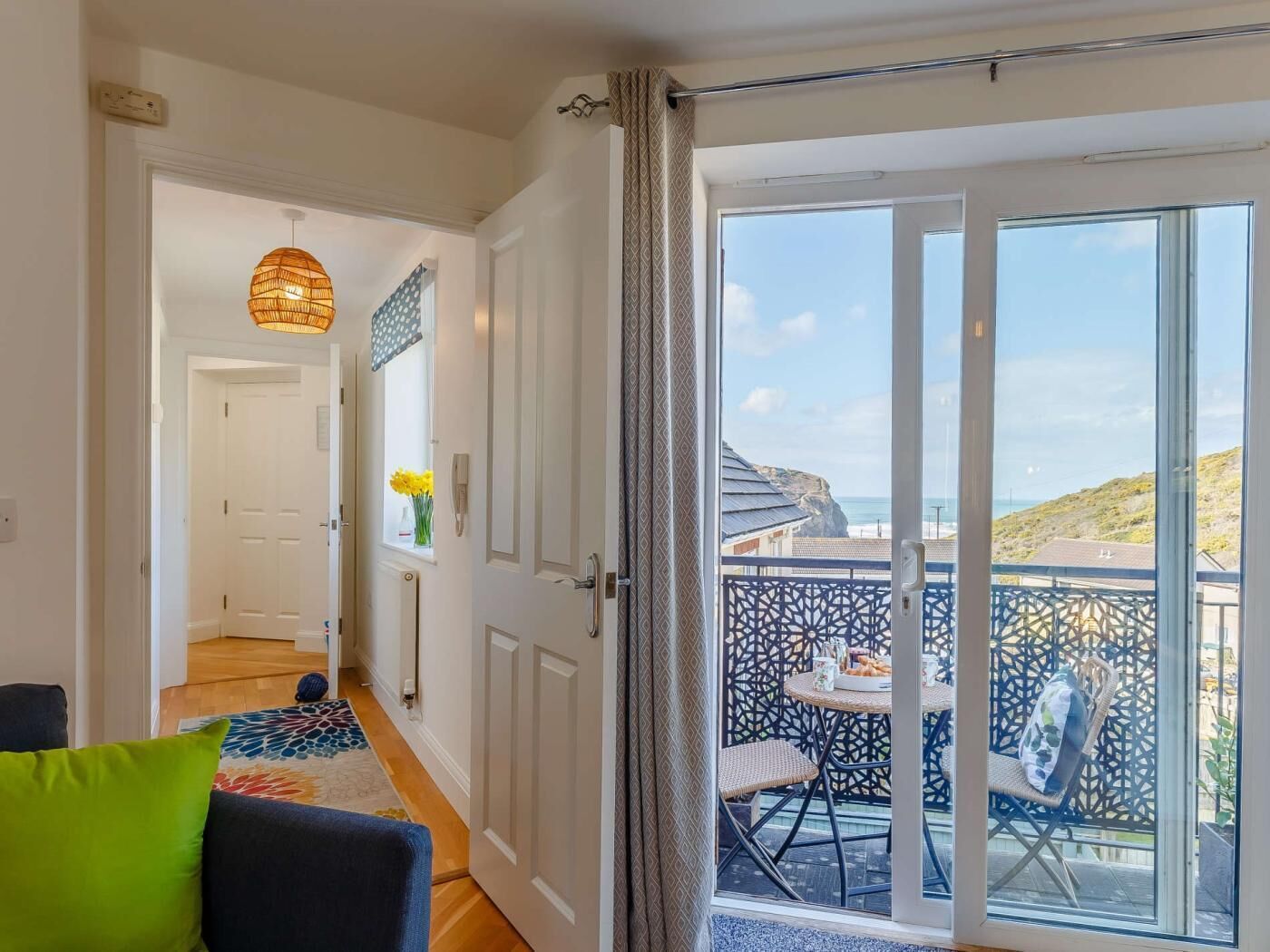 A room with a sliding glass door leading to a balcony with a view of the sea.