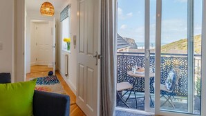 Una habitación con puerta de vidrio corredera que da a un balcón con vista al mar.