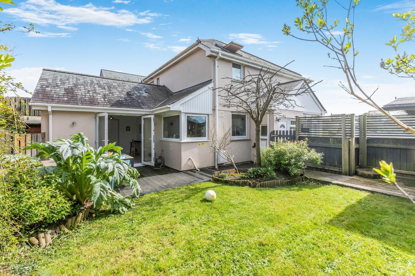 A two-story house with a covered patio, a fenced backyard, and a well-maintained lawn.