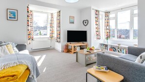 A modern living room with a sofa, a coffee table, a TV, and a bookshelf. - 3 Bed in Bude (oc-86665) (Bude)