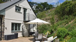 Ein zweistöckiges Haus mit einer Wendeltreppe, Sitzgelegenheiten im Freien und einer Terrassenfläche.