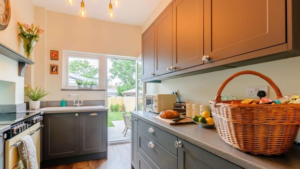 A modern kitchen with dark cabinets, a central island, a built-in oven, and a hanging light fixture. - 3 Bed in Broadstairs (oc-86736) (Broadstairs)