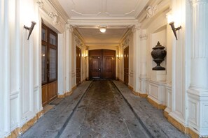 A hallway with a stone floor, white walls, and wooden doors. - Luxe, State of the Art Suite near Montmartre (Paris)