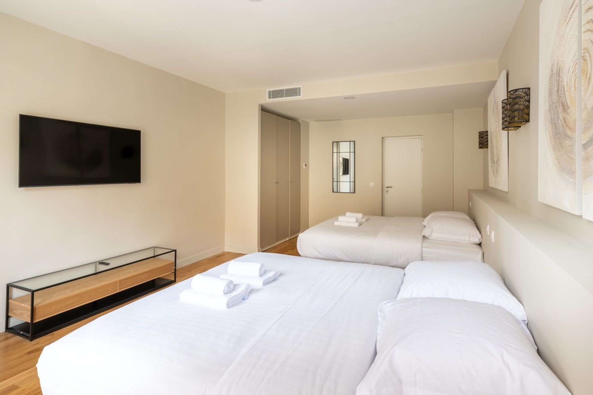 Ein Hotelzimmer mit zwei Betten, einem Fernseher, einem Spiegel und einem Kleiderschrank.