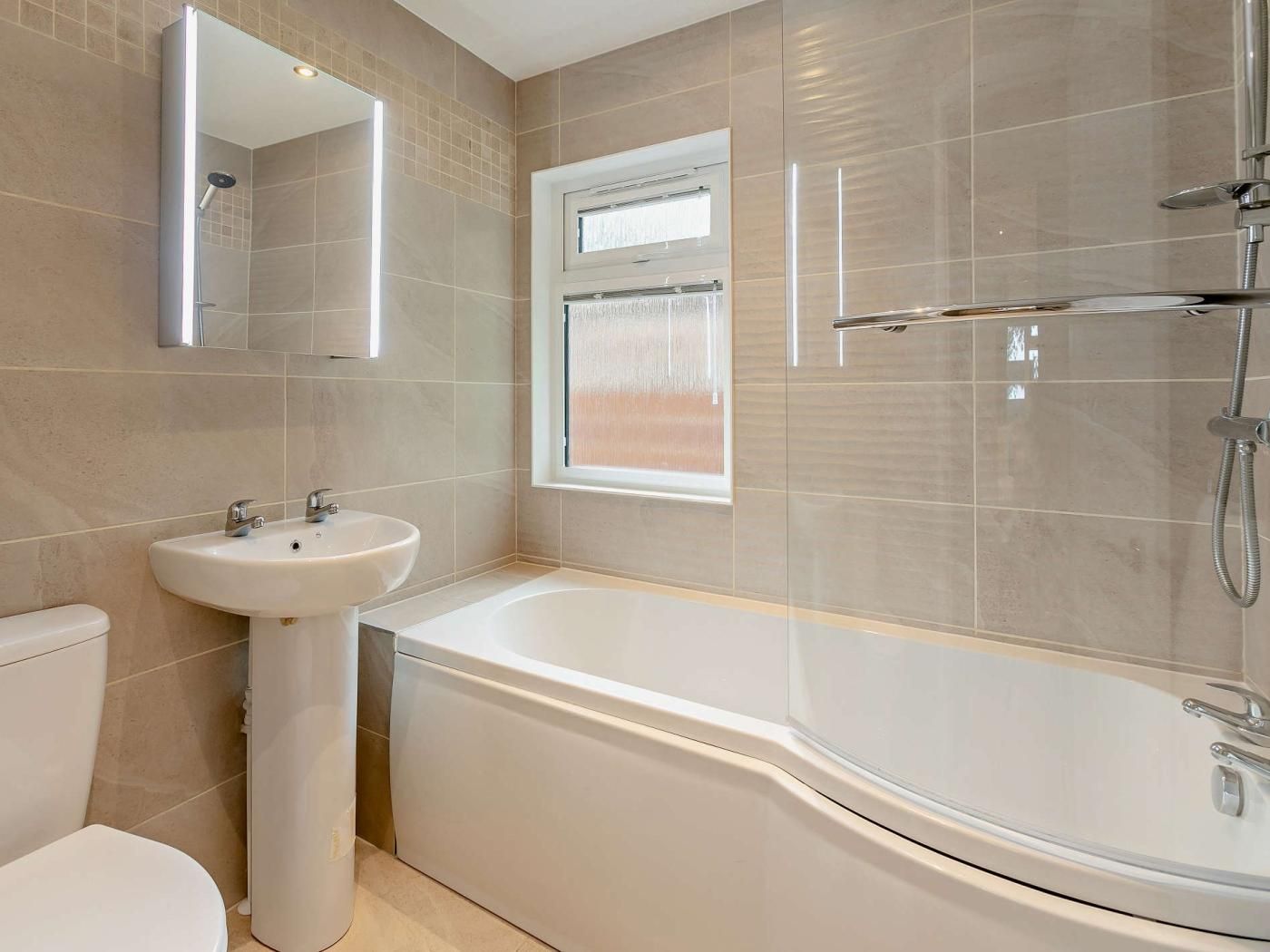 A modern bathroom with a freestanding bathtub, a pedestal sink, and a toilet.