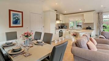 A modern kitchen with white cabinets, a dining area with a table set for four, and a living area with a sofa.
