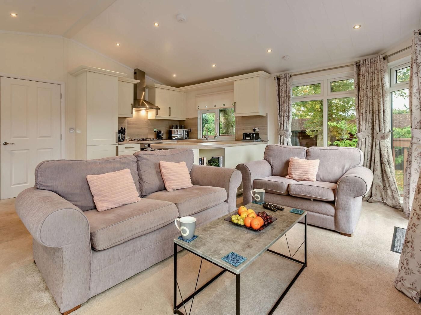 A modern living room with two sofas, a coffee table, and a kitchen in the background.