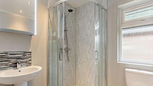 Une salle de bain moderne avec une douche à parois de verre, un lavabo blanc et des toilettes.
