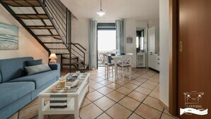A living room with a sofa, coffee table, and a staircase. - Palazzo Carrano (Vietri sul Mare)