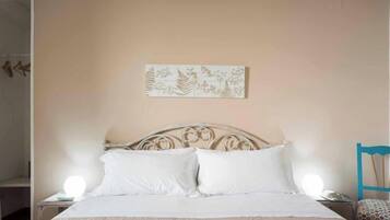 A bedroom with a bed, two bedside lamps, a wall-mounted artwork, and a chair.