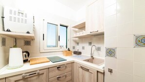 A compact kitchen with a window, a sink, and a countertop with a kettle and a cutting board. - Palazzo Carrano (Vietri sul Mare)